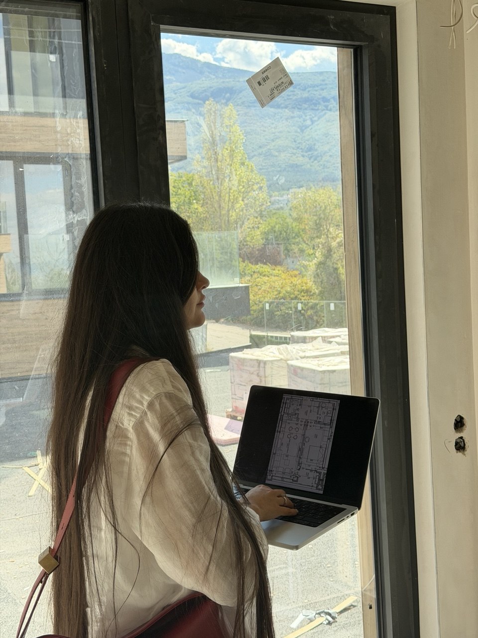 Client reviewing floor plans on a property viewing, overlooking a Sofia construction site and the surrounding mountains